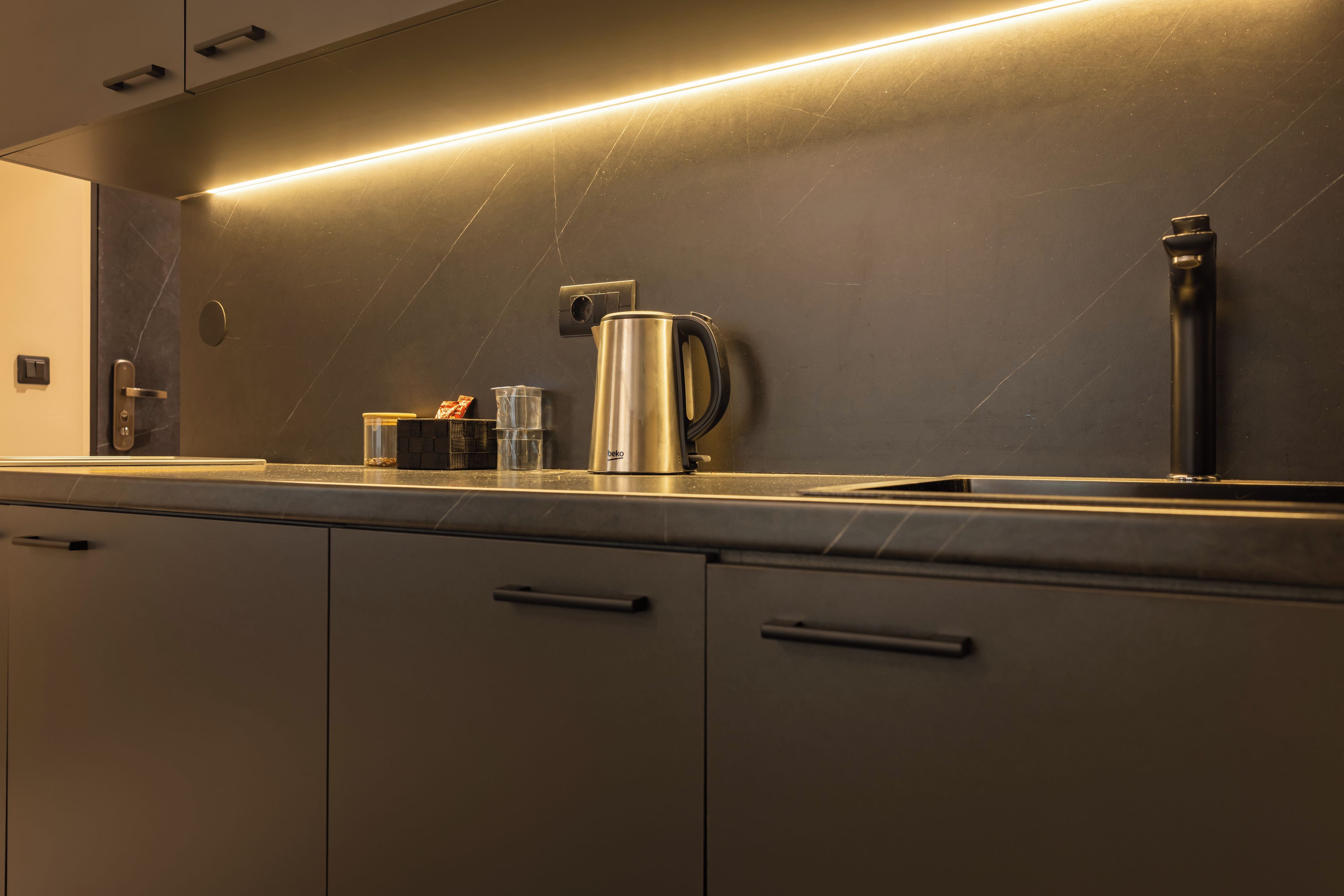 Een moderne keuken met een strak aanrecht, een koffiezetapparaat en een waterkoker.
