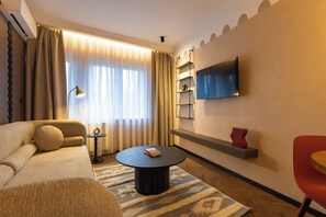 Una sala de estar moderna con un sofá, una mesa de centro, un televisor montado en la pared y una silla roja.
