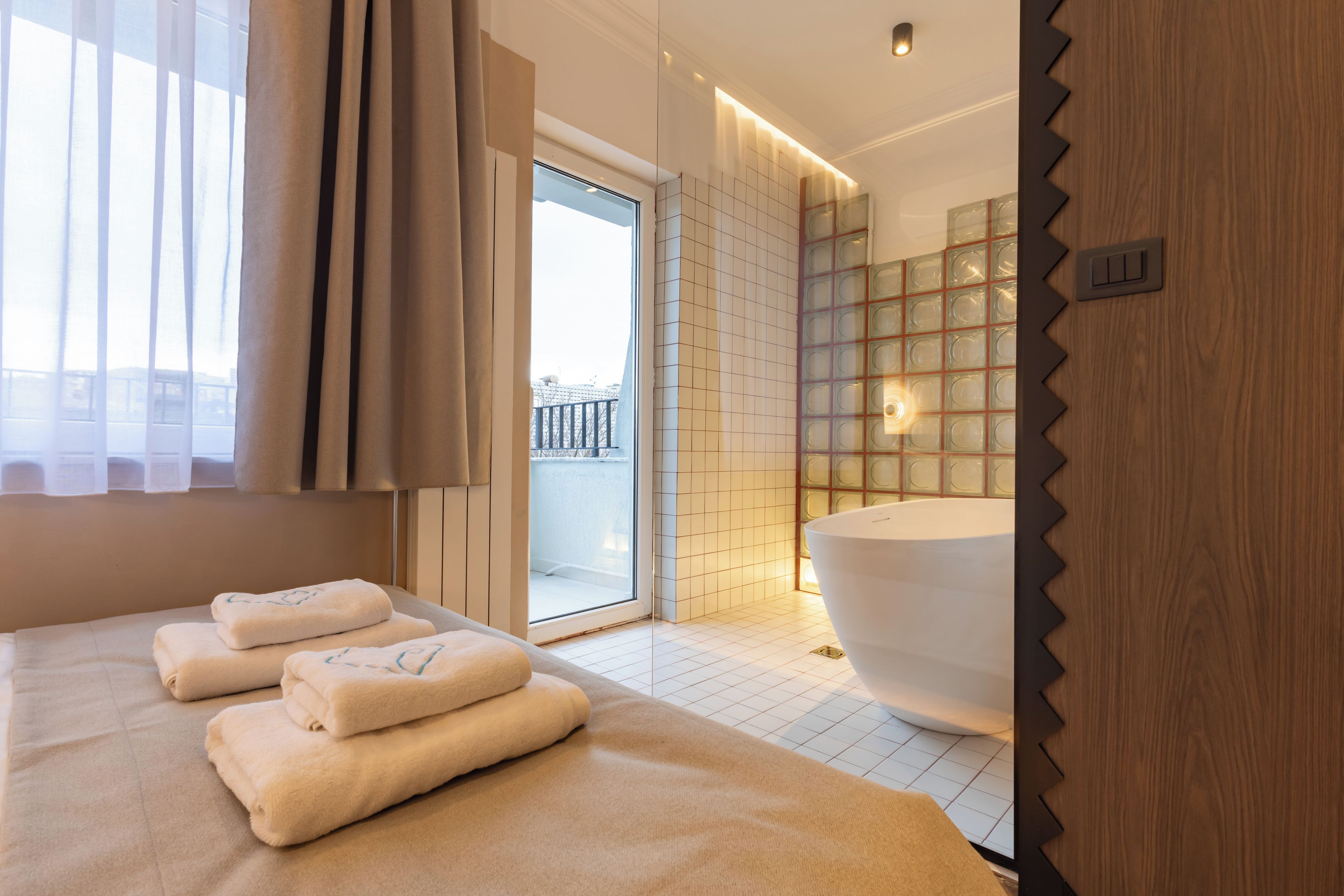 Un baño moderno con una bañera grande, una cabina de ducha con paredes de vidrio y vistas al exterior.