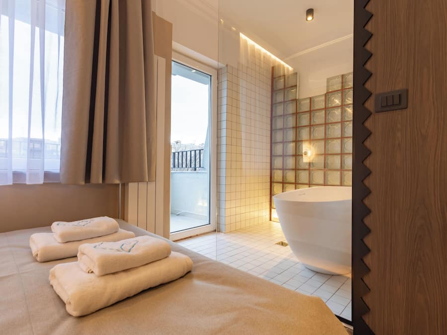 A modern bathroom with a large bathtub, a glass shower enclosure, and a view of the outdoors.