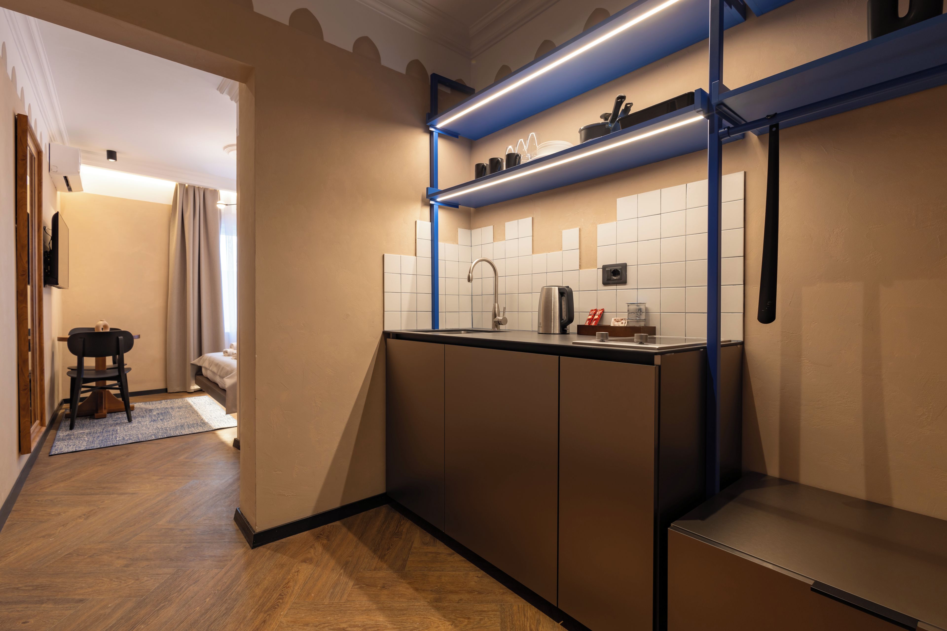 A compact kitchen with a built-in oven, a coffee maker, and a kettle on the counter.