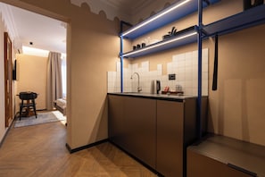 Una cocina compacta con horno integrado, cafetera y hervidor en la encimera.