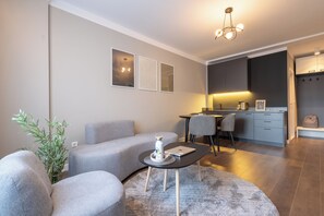 Una sala moderna con un sofá gris, una mesita redonda y una planta en maceta.
