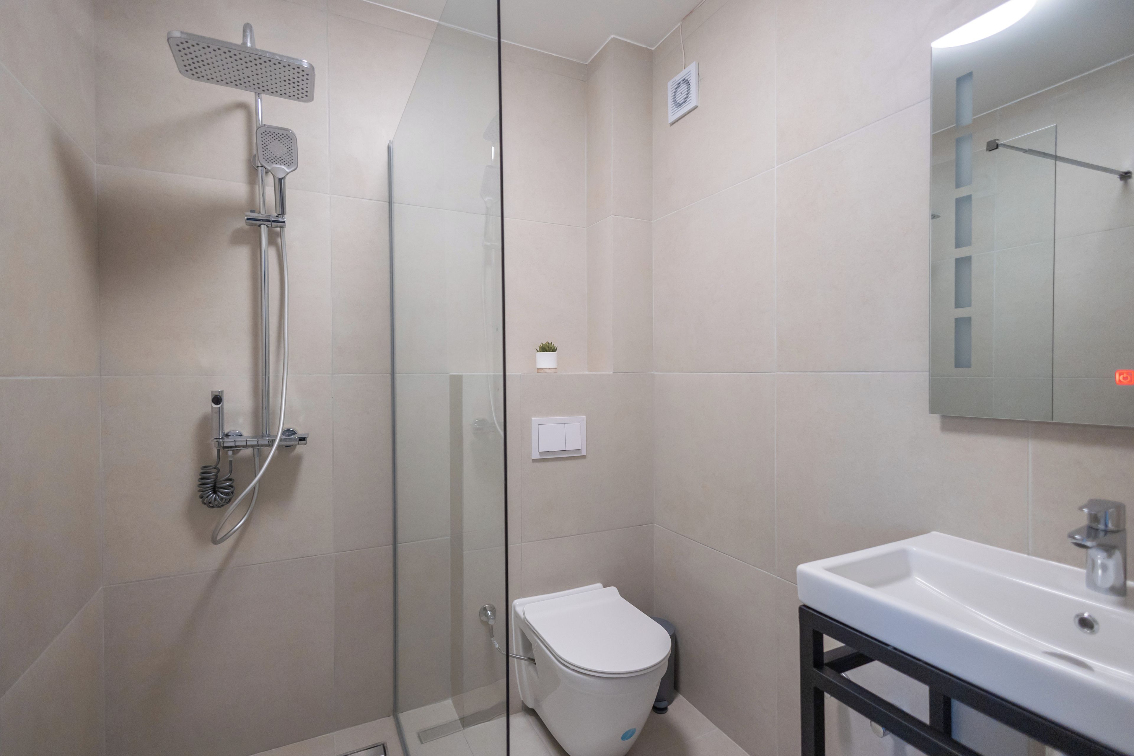 A modern bathroom with a glass-enclosed shower, a white toilet, and a sink with a black frame.