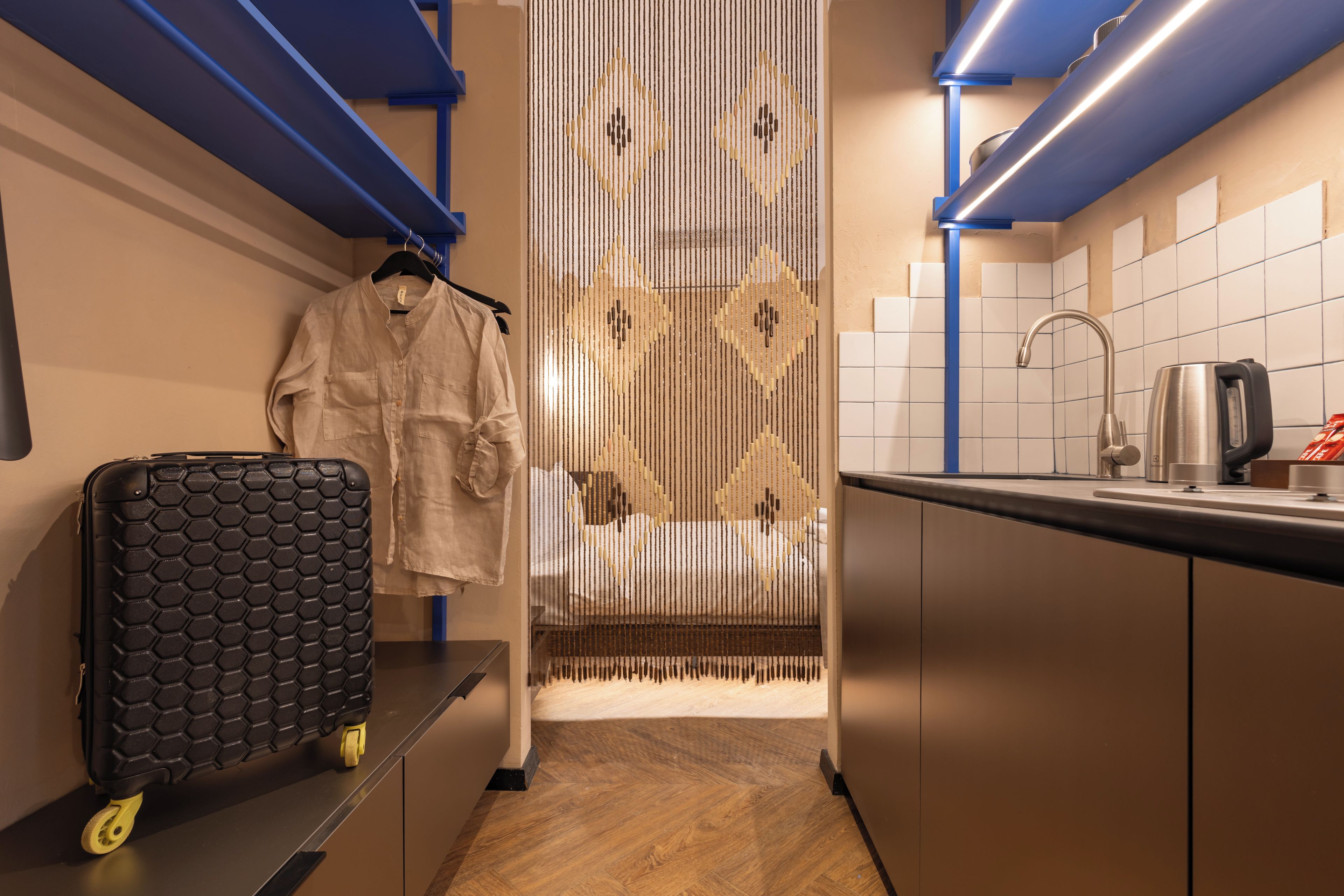 A compact kitchen with a sink, kettle, and a decorative vertical panel.