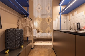 A compact kitchen with a sink, kettle, and a decorative vertical panel. - Prishtina City Apartments (Pristina)