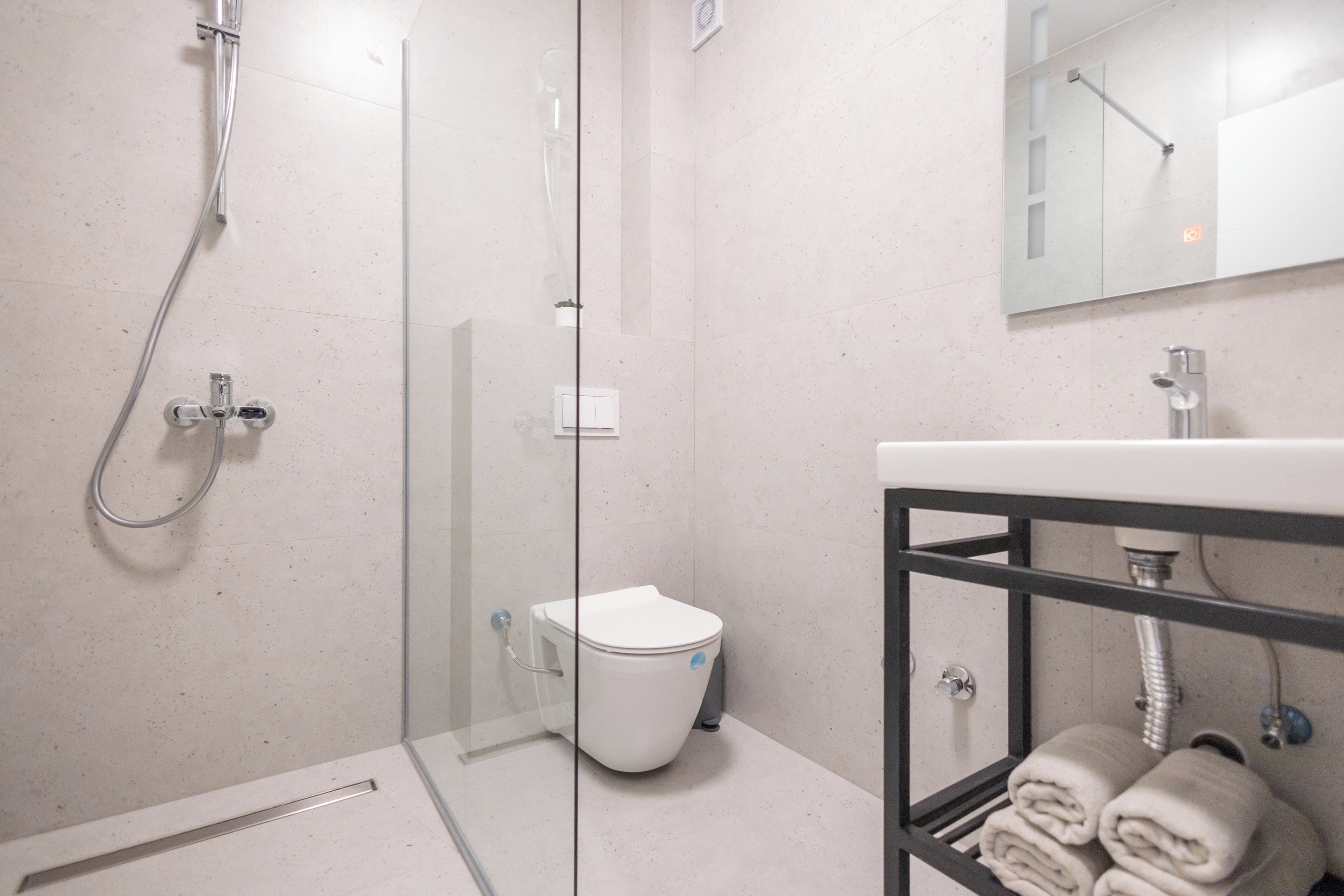 Ein modernes Badezimmer mit Duschkabine aus Glas, einer weißen Toilette und einem Waschbecken mit Handtuchhalter.