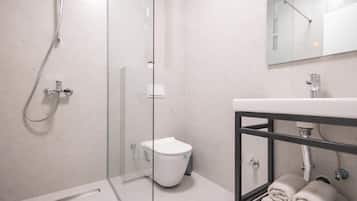 Ein modernes Badezimmer mit Duschkabine aus Glas, einer weißen Toilette und einem Waschbecken mit Handtuchhalter.