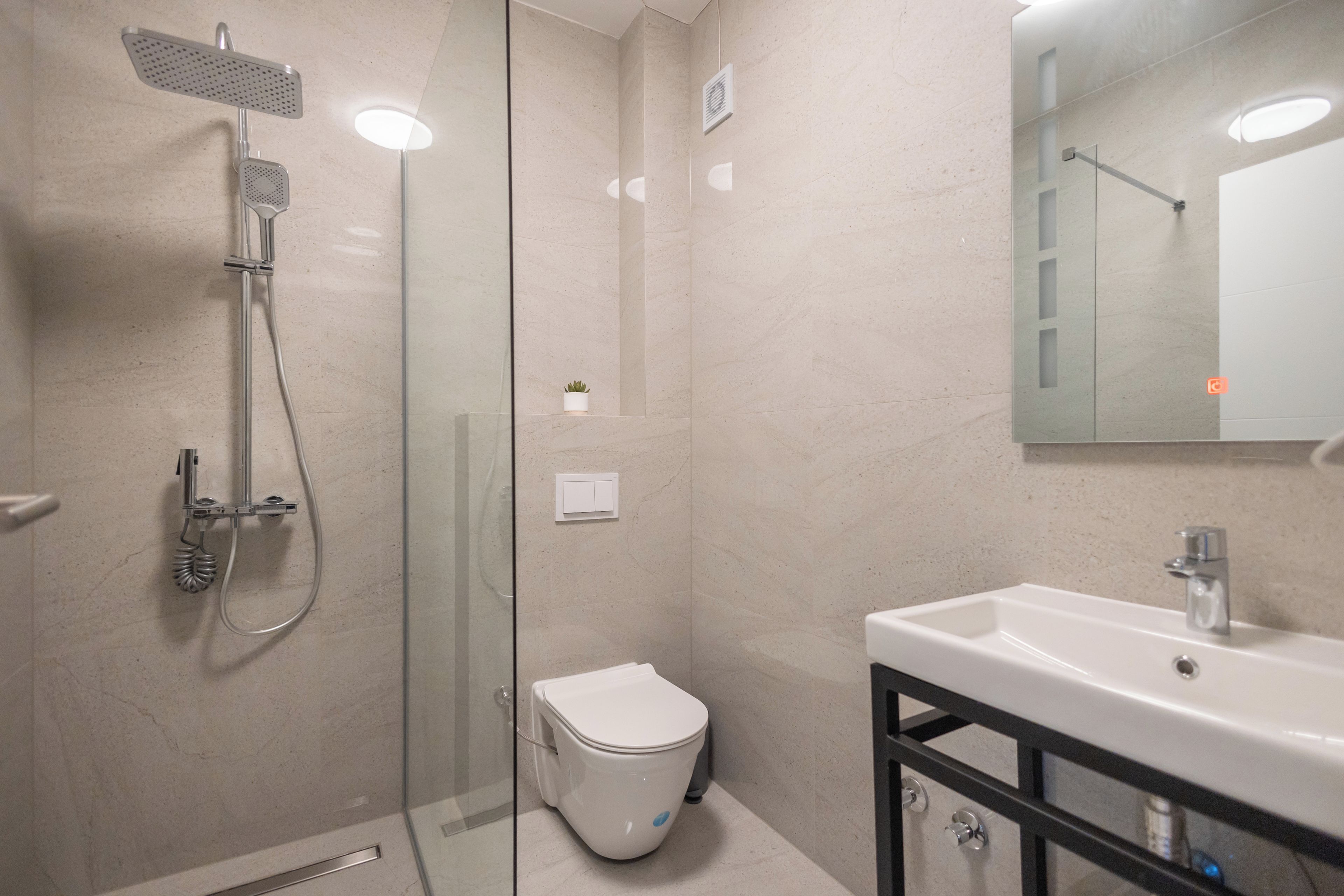 Ein modernes Badezimmer mit einer Duschkabine aus Glas, einer weißen Toilette und einem Waschbecken mit schwarzem Rahmen.