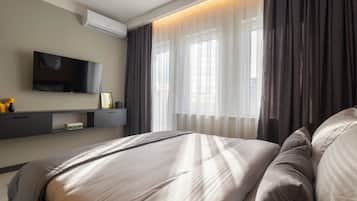Een moderne hotelkamer met een bed, een flatscreen televisie, een nachtkastje en een raam met gordijnen.