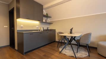 Een moderne keuken met een inbouweiland, een eethoek met tafel en stoelen, en een klein zithoekje met een bank.