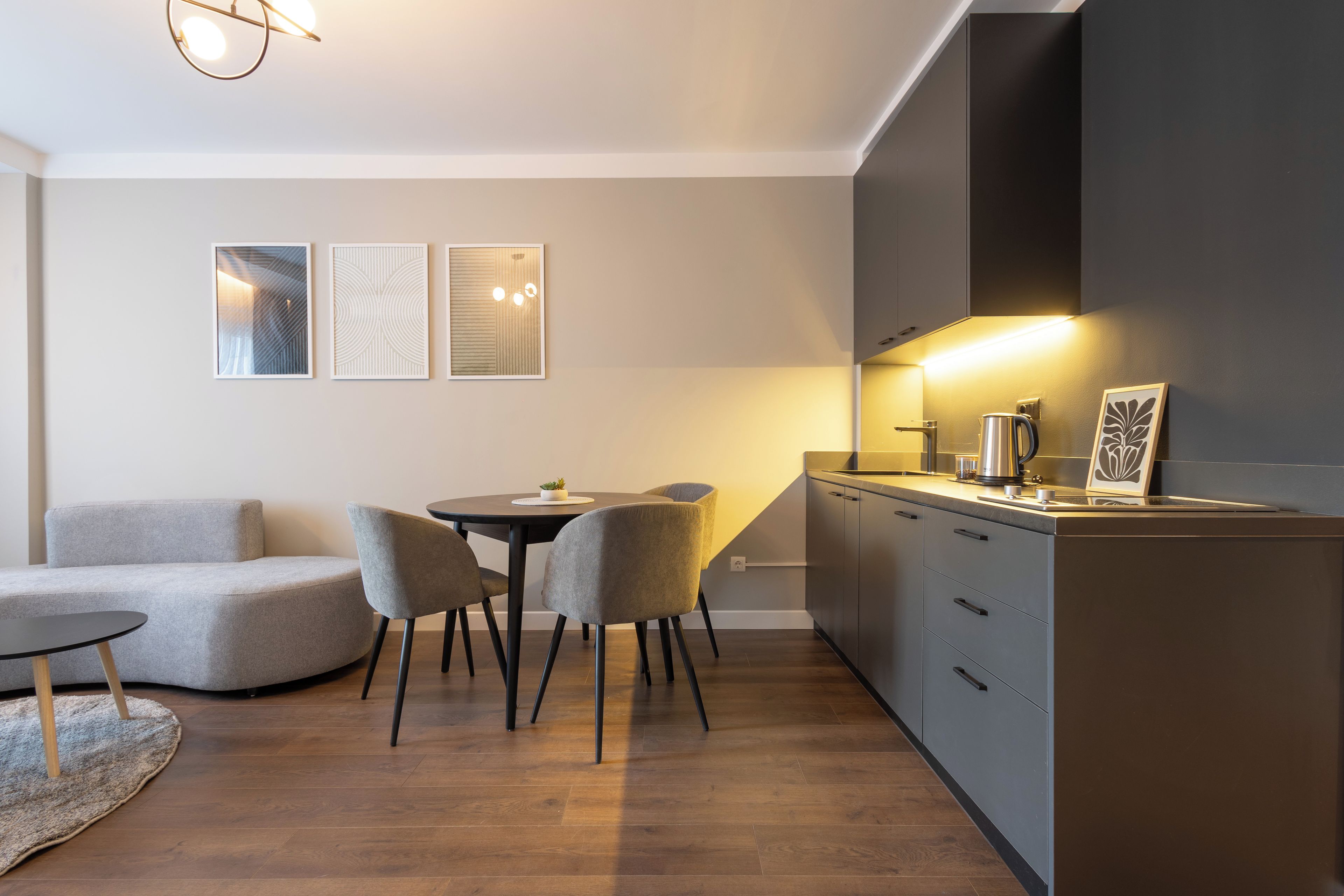 Una cucina moderna con zona pranzo, che include un tavolo rotondo, due sedie e un divano.