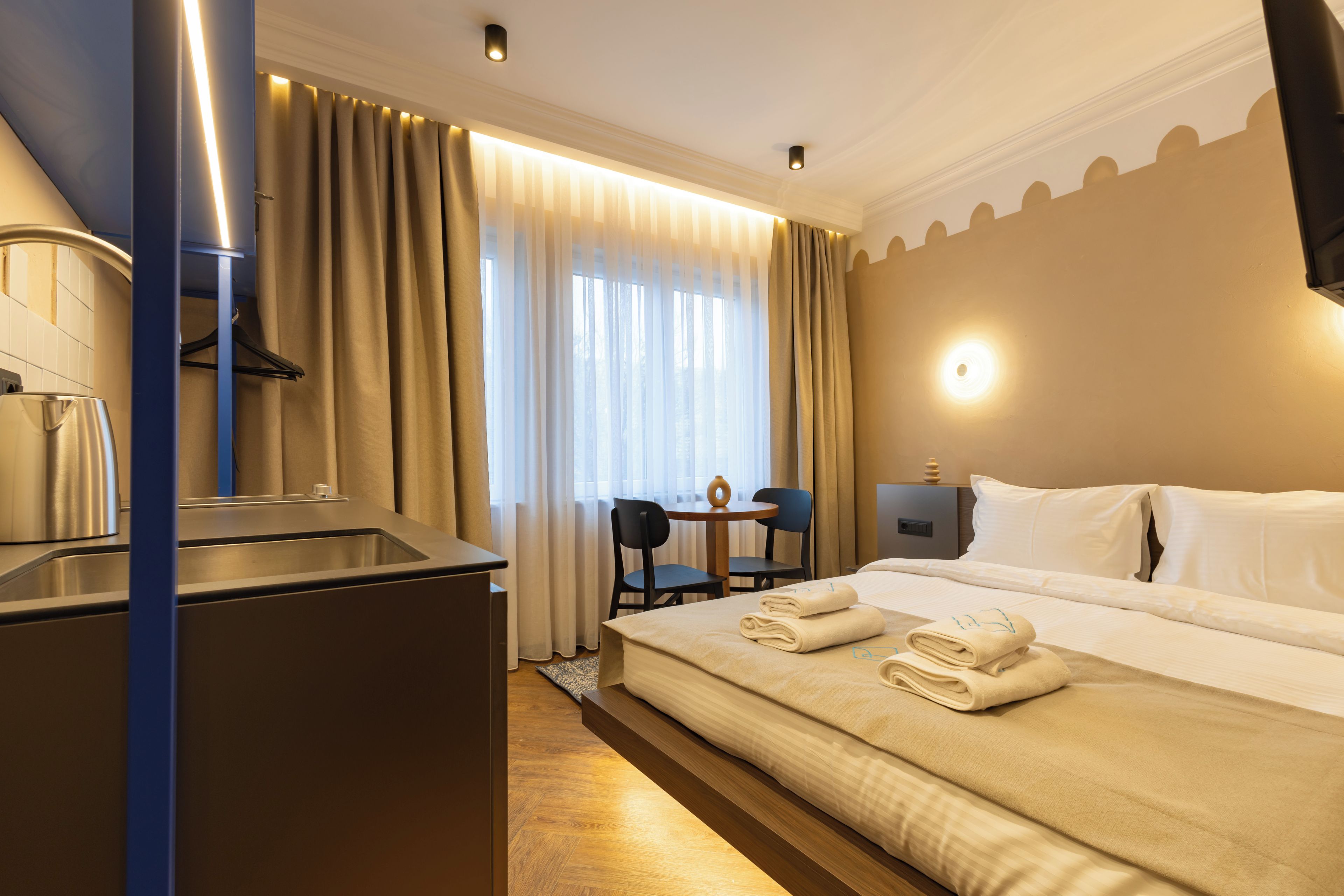 Habitación de hotel con una cama, un escritorio, una silla, cafetera y televisión.