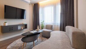 Una sala de estar moderna con una televisión de pantalla plana, un sofá, una mesa de centro y una mesita auxiliar.