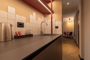 Una cocina moderna con hervidor de acero inoxidable, cafetera y pileta integrada.