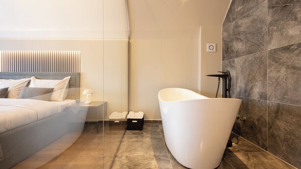 Un baño moderno con una bañera independiente, un espejo grande y un lavamanos con pileta.