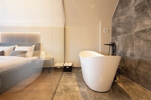 Un baño moderno con una bañera independiente, un espejo grande y un lavamanos con pileta.