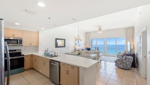 A modern kitchen with a central island, a dining area with a view, and a living room with a balcony overlooking the ocean. - Beautiful condo with fabulous views at Sterling Beach! Open Labor Day weeekend (Panama CIty Beach)