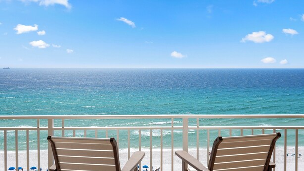A balcony with two chairs overlooking a beach with a ship in the distance. - Beautiful condo with fabulous views at Sterling Beach! Open Labor Day weeekend (Panama CIty Beach)