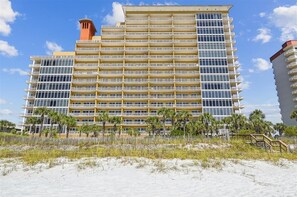 Um hotel com vários andares, fachada uniforme, varandas e vista para a praia.