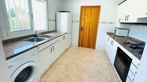 A compact kitchen with a washing machine, a stove, and a microwave. - SAONA VILLAS (VN ELEN): villa for 6 people, private pool, wifi, air conditioning (Les Tres Cales)