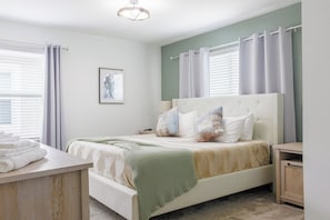 A bedroom with a bed, bedside tables, a bedside lamp, a framed picture on the wall, and a window with curtains. - Entire Beautiful 5-bedroom Rental Minutes From Disney!  -No Pets Allowed- (Davenport)