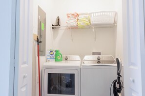 A laundry area with a washing machine, dryer, and stacked towels. - Entire Beautiful 5-bedroom Rental Minutes From Disney!  -No Pets Allowed- (Davenport)