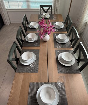 A dining table set for eight with white plates, glasses, and a vase of pink flowers. - Entire Beautiful 5-bedroom Rental Minutes From Disney!  -No Pets Allowed- (Davenport)