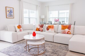 A modern living room with a white sofa set, a round coffee table, and a patterned rug. - Entire Beautiful 5-bedroom Rental Minutes From Disney!  -No Pets Allowed- (Davenport)