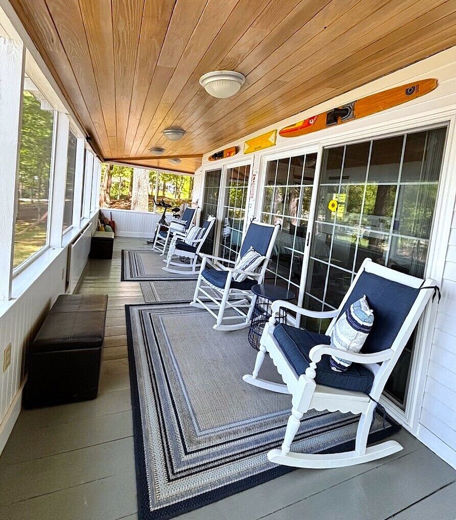 Une véranda abritée avec des fauteuils à bascule, un banc et une vue sur l’extérieur.
