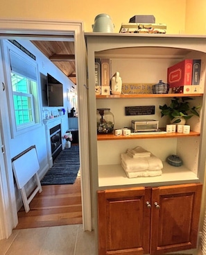 A cozy kitchen with a fireplace, wooden cabinets, and a shelf with various kitchen items.