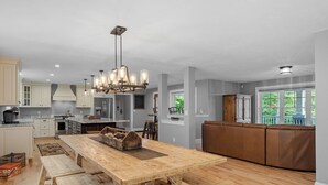 A spacious kitchen with wooden countertops, a large dining table, and a modern chandelier. - Sunset Retreat at Dockham Shore (Gilford)
