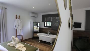 A modern bathroom with a freestanding bathtub, a vanity with a mirror, and a towel rack with robes.