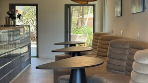 A modern interior with a round table, cushioned seating, and a hanging light fixture. - Hôtel confidentiel Le Grécale **** (Pianotolli-Caldarello)