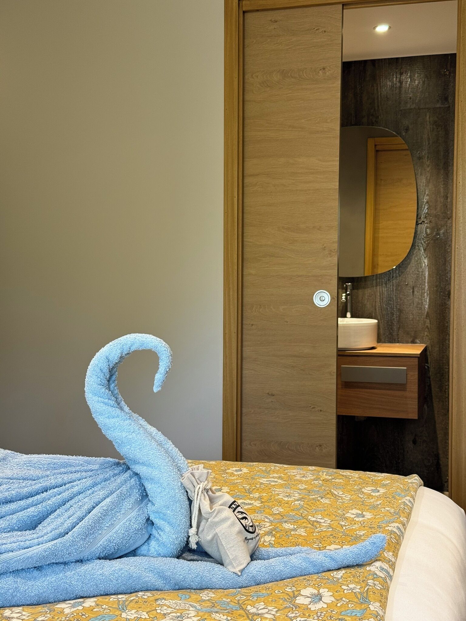 Una camera d'albergo con un letto, un armadio in legno, uno specchio e un piccolo bagno.