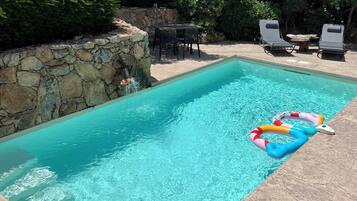 Relax by the pool surrounded by lush greenery and lounge chairs.