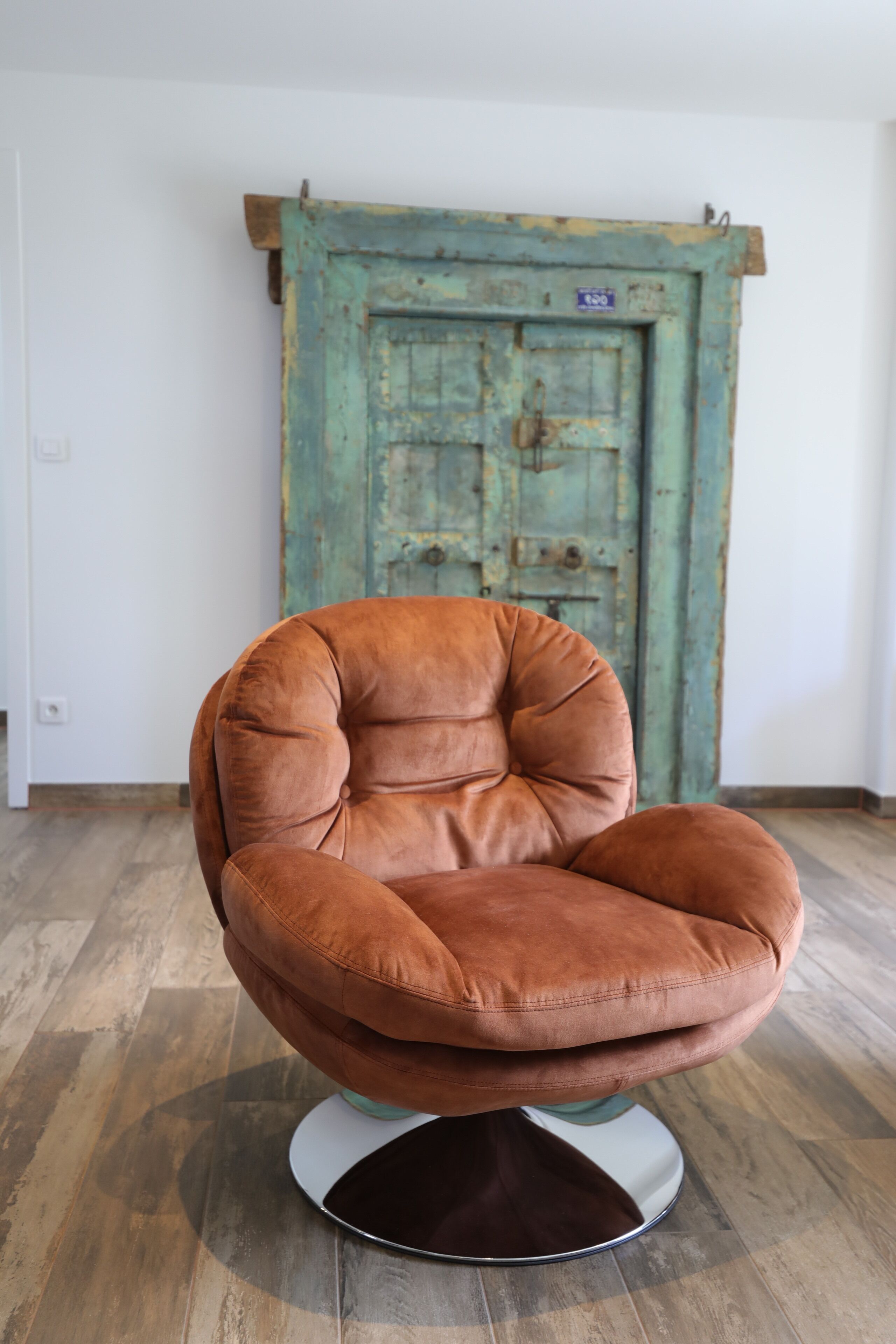 A brown leather chair with a cushioned seat and backrest, positioned on a white pedestal base.
