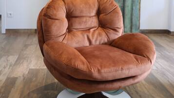 A brown leather chair with a cushioned seat and backrest, positioned on a white pedestal base.