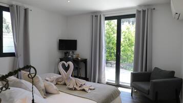 Un dormitorio moderno con cama, escritorio, televisor y vistas a zonas verdes.