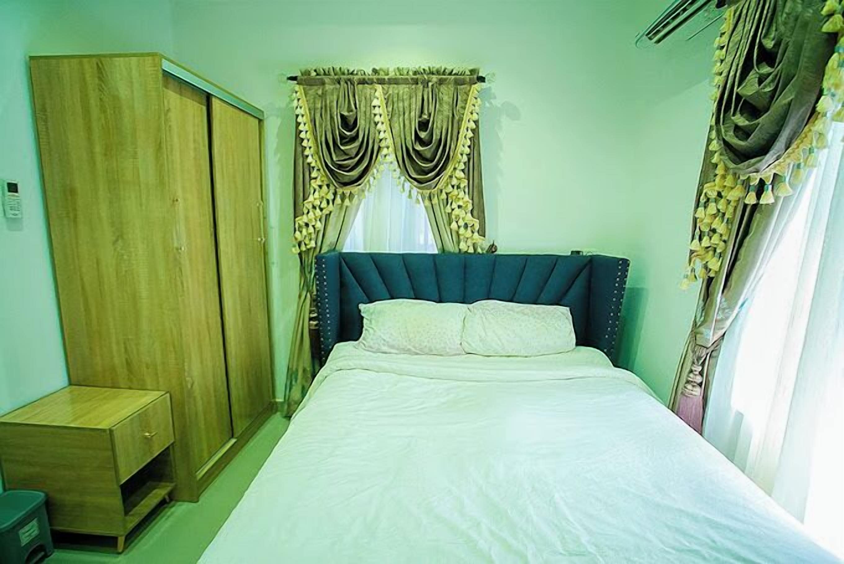 A bedroom with a bed, a wardrobe, and curtains.