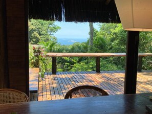 A wooden deck with a view of lush greenery and the ocean.