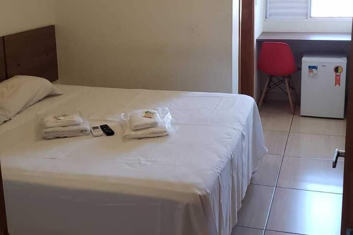 Une chambre d’hôtel équipée d’un lit, d’un bureau, d’une chaise et d’un petit réfrigérateur.