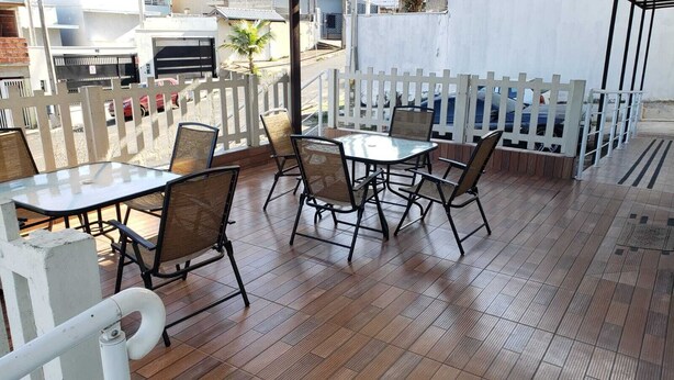 An outdoor patio area with wooden flooring, metal tables, and chairs. - Hotel Viracopos de Indaiatuba Ltda EPP (Indaiatuba)