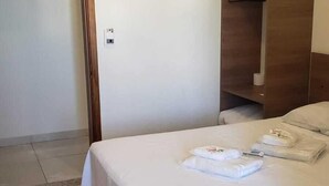 A hotel room with a bed, a wooden wardrobe, and a door. - Hotel Viracopos de Indaiatuba Ltda EPP (Indaiatuba)