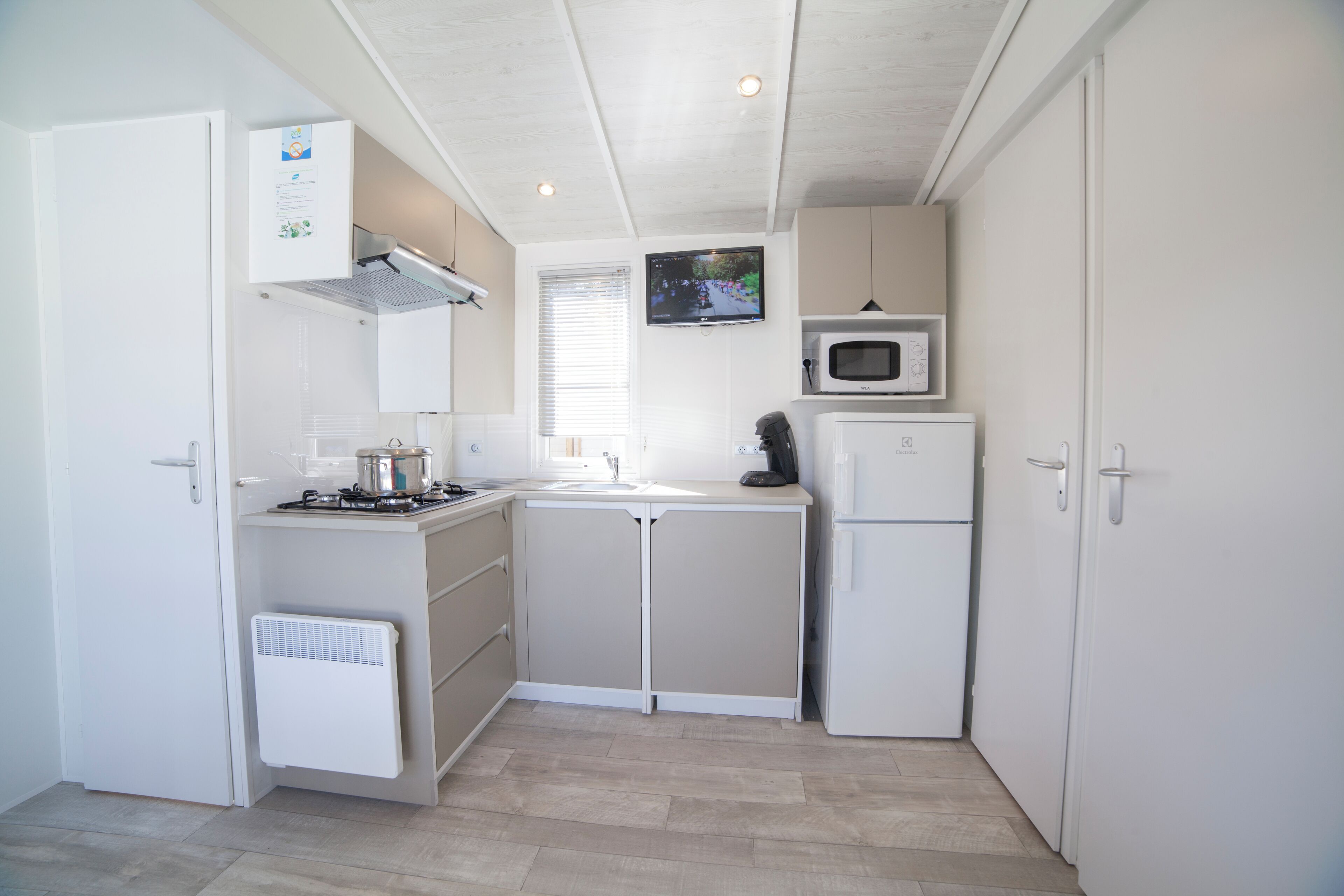 A compact kitchen with white cabinets, a microwave, a stove, and a refrigerator.