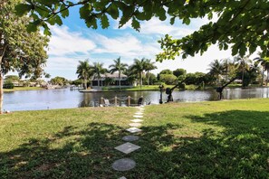 Un camino que lleva a una zona junto al lago, con un quiosco y palmeras.