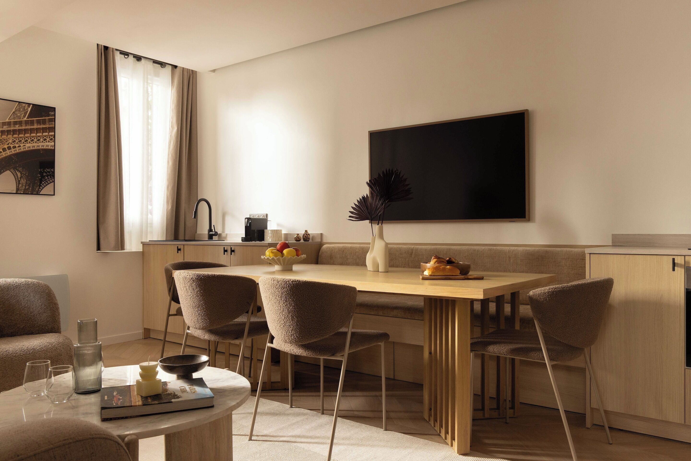 Un comedor moderno con una mesa de madera, cuatro sillas y un gran ventanal con cortinas.