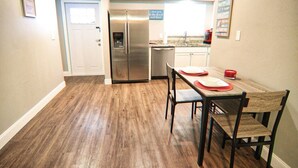 A compact kitchen with a refrigerator, a dining table with chairs, and a small island. - The Cape 3 Gulf access (Cape Coral)