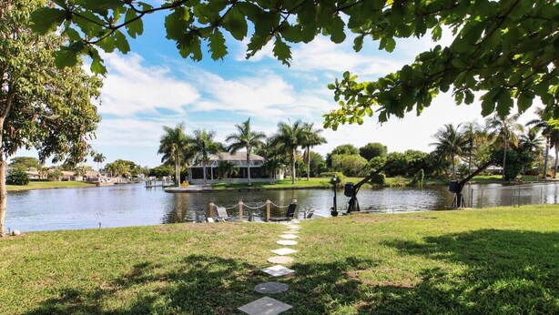 A pathway leading to a lakeside area with a gazebo and palm trees. - The Cape 3 Gulf access (Cape Coral)