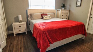 A bedroom with a bed, nightstand, dresser, and a window. - The Cape 3 Gulf access (Cape Coral)